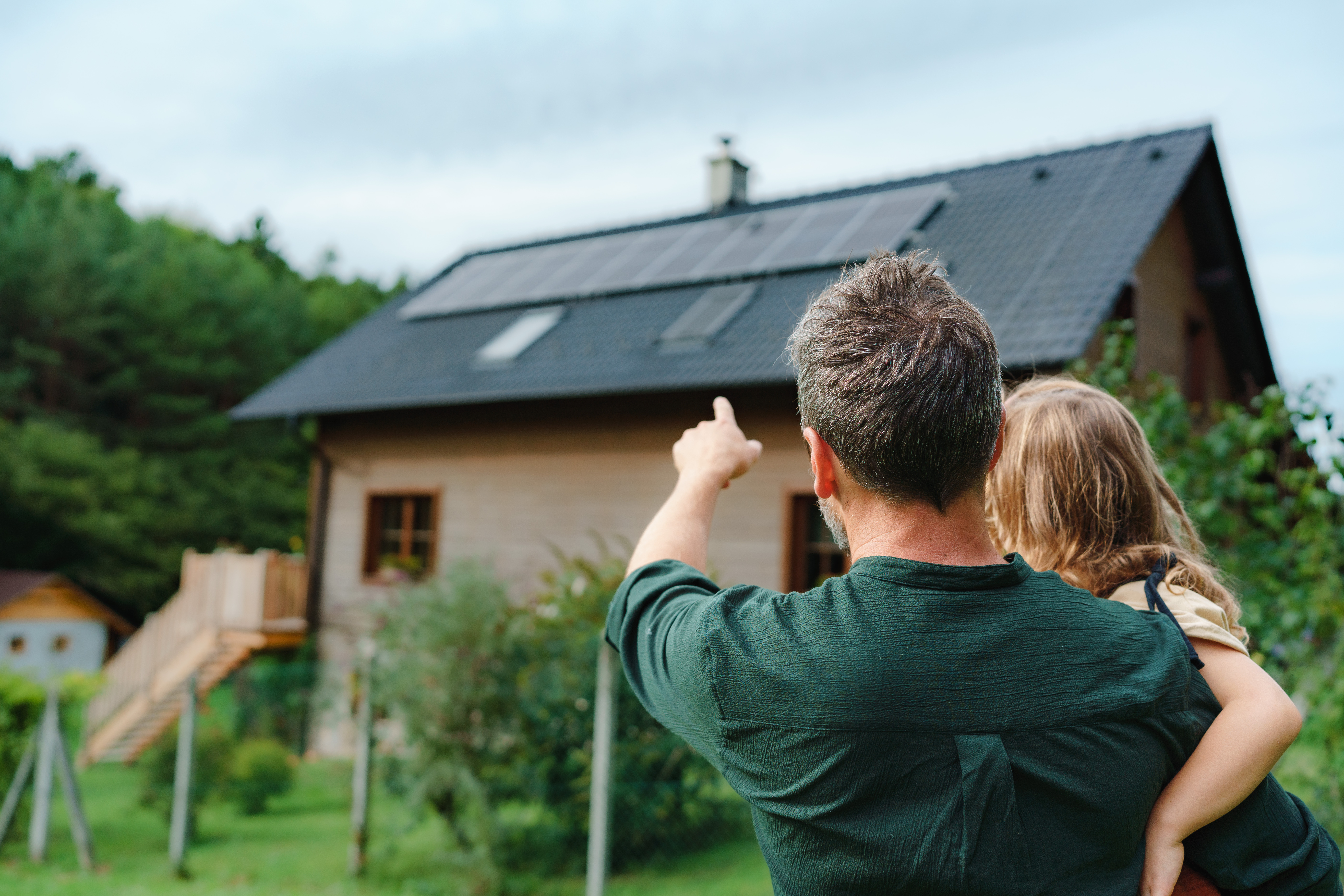 Familie blickt auf ihr Haus mit Photovoltaikanlage